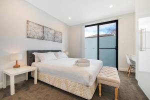a white bedroom with a bed and a table and a chair at BRID243FL - The Terrace on Bridge in Sydney
