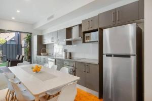 a kitchen with a white table and a stainless steel refrigerator at BRID243FL - The Terrace on Bridge in Sydney