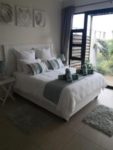 1 cama blanca grande en un dormitorio con ventana en Blissful Beachfront Apartment - 11 Sovereign sands en KwaDukuza