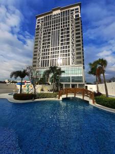 un grand bâtiment avec une piscine en face d'un bâtiment dans l'établissement The Excelsior Hotel Las Piñas, à Manille