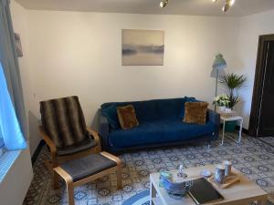 ein Wohnzimmer mit einem blauen Sofa und einem Sessel in der Unterkunft En mode Pause in Dinant