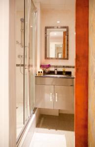 uma casa de banho com um lavatório e um chuveiro com um espelho. em City Inn Russell Square em Londres