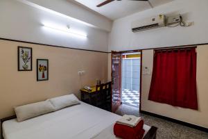 a bedroom with a bed and a red curtain at ANADIYIL LEELAKRISHNA INN in Cochin