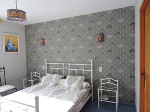 a bedroom with a white bed and a gray wall at Le Moulin du Barthas in Montredon-Labessonnié