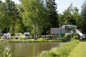 ein Haus und zwei Wohnwagen neben einem Fluss in der Unterkunft Wiesner's Teichwirtschaft in Scheibenberg
