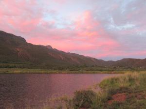 una puesta de sol sobre un lago con montañas en el fondo en The Country Garden, en Ladismith