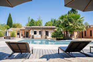 a swimming pool with two chairs and a house at Le Mas du Cheval in Lattes