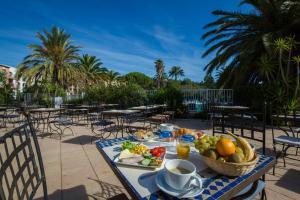 a table with a bowl of fruit on a table with chairs at SOWELL Family Hôtel Port Grimaud in Grimaud