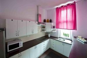 una cocina con armarios blancos y una ventana roja en Apartamenty Parkowe, en Bydgoszcz