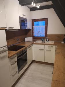 eine Küche mit weißen Schränken, einem Waschbecken und einem Fenster in der Unterkunft Ferienhaus Fynnhütte in Schwarzenborn