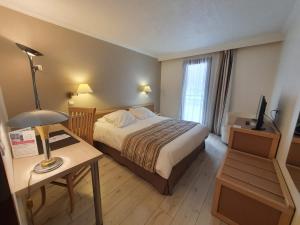 Habitación de hotel con cama y mesa con lámpara en Hotel Amélie en Brides-les-Bains