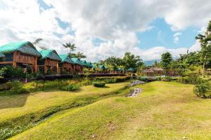 a resort with a grassy field and a river in front at Your Brothers House Tribal Village in Legazpi