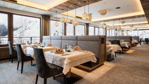 - un restaurant avec des tables, des chaises et de grandes fenêtres dans l'établissement Hotel Almhof, à Galtür