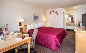 um quarto de hotel com uma cama vermelha, uma secretária e uma mesa em Hollister Inn em Hollister