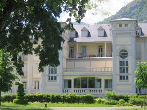 un grand bâtiment blanc avec un arbre dans l'établissement Le Balcon du Parc, entre Lourdes et Gavarnie, à Argelès-Gazost