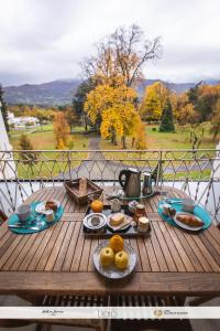 einen Holztisch mit Essen auf dem Balkon in der Unterkunft Le Balcon du Parc, entre Lourdes et Gavarnie in Argelès-Gazost