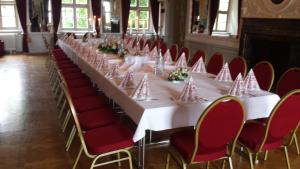 una mesa larga en una habitación con sillas rojas en Stadtschloß Hecklingen***, en Hecklingen