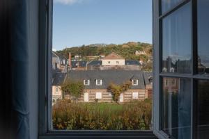 une fenêtre ouverte avec vue sur une maison dans l'établissement L'Escapade - Maison avec petit jardin - 4 pers, à Étretat