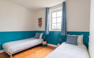 - 2 lits dans une chambre aux murs bleus et blancs dans l'établissement L'Escapade - Maison avec petit jardin - 4 pers, à Étretat