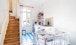 une cuisine avec une table et des chaises ainsi qu'un escalier dans l'établissement L'Escapade - Maison avec petit jardin - 4 pers, à Étretat