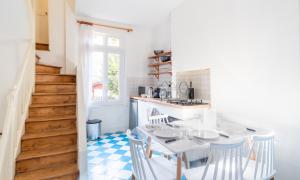 une cuisine avec une table et des chaises ainsi qu'un escalier dans l'établissement L'Escapade - Maison avec petit jardin - 4 pers, à Étretat