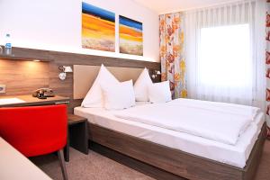Schlafzimmer mit einem Bett, einem Schreibtisch und einem roten Stuhl in der Unterkunft GenoHotel Karlsruhe in Karlsruhe + 12 Fotos