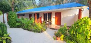 una pequeña casa con una puerta roja y una mesa en Thoddoo Island Life, en Thoddoo