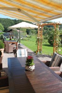 einen Holztisch auf einer Terrasse mit Sonnenschirm in der Unterkunft Hainbuchhof in Anger