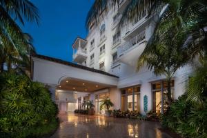 ein großes weißes Gebäude mit Palmen davor in der Unterkunft The Lago Mar Beach Resort and Club in Fort Lauderdale