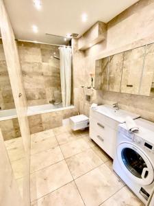 a bathroom with a washing machine and a tub at Rezydencja Wind Rose - luxury ApartHotel Gdansk in Gdańsk