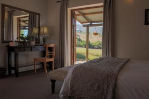 Schlafzimmer mit einem Bett, einem Schreibtisch und einem Fenster in der Unterkunft Zebra Cottage and Lodge in Stellenbosch