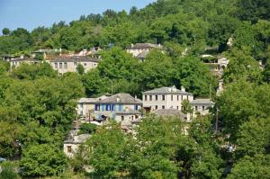 a group of houses on a hill with trees at Mystic Lake in Koukkoúlion