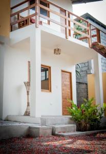 a white house with a wooden door and stairs at Tagualodge Hostel Manglaralto in Manglaralto