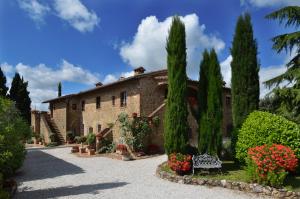 a house with trees and a bench in front of it at Agriturismo La Casa Nuova in Castelmuzio