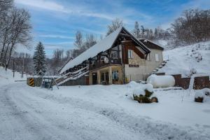a house covered in snow next to a snowy road at Gospoda i Noclegi Na szlaku in Kudowa-Zdrój