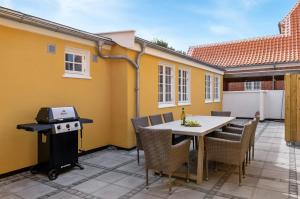 een patio met een tafel en stoelen en een grill bij 1 Skøn og lyst indrettet feriehus i Skagen in Skagen