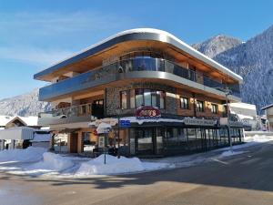 Un gran edificio con nieve delante. en Mo's Apartments, en Mayrhofen