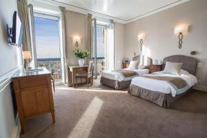 a hotel room with two beds and a balcony at Hotel Splendid in Cannes