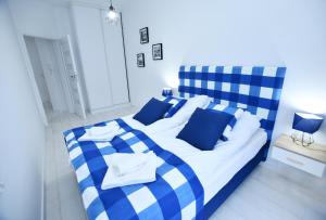 a blue and white bed with blue and white pillows at Sunset Resort, Nadmorska 106 in Grzybowo