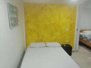 ein Schlafzimmer mit einem Bett und einer gelben Wand in der Unterkunft San San Andrés Little House 3 by BBBSAI in San Andrés