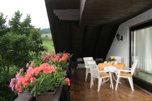 eine Terrasse mit einem Tisch, Stühlen und Blumen in der Unterkunft Ferienwohnung Lydia Schaeck in Oberharmersbach