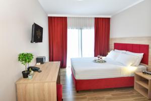 a bedroom with a large bed with red curtains at Hotel Palladium Sithonia in Kalamitsi