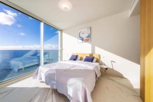 een slaapkamer met een bed en een groot raam bij Barreirinha Front-Line Sea View II by HR Madeira in Funchal
