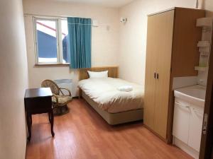 a small bedroom with a bed and a window at Alpine Guesthouse in Furano +8 photos