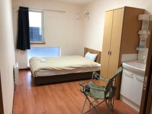 a small room with a bed and a chair in it at Alpine Guesthouse in Furano