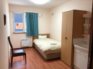 a small bedroom with a bed and a window at Alpine Guesthouse in Furano