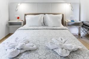 
a bed with white sheets and pillows on top of it at Artemis Cynthia Complex in Paphos City
