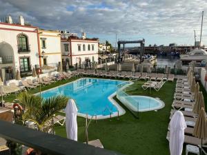 einem Pool mit Rutsche neben einem Yachthafen in der Unterkunft Billy's Beachfront Apartment with pool access in Puerto de Mogán