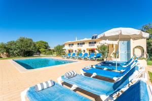 a pool with chairs and umbrellas next to a building at Villa Misofia in Almancil