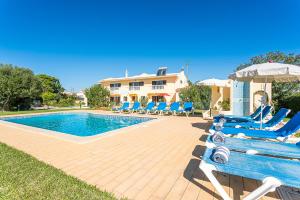 a pool with chairs and an umbrella and a house at Villa Misofia in Almancil